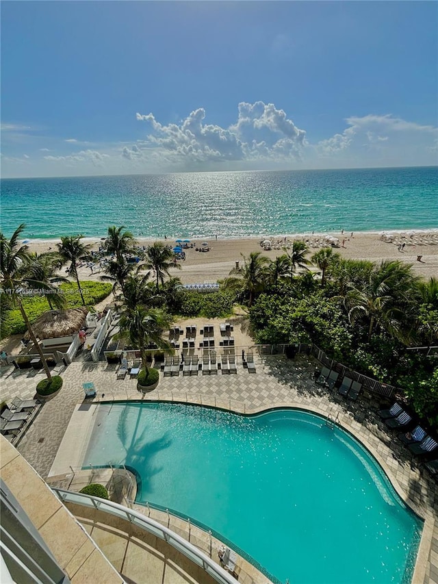 view of swimming pool with a water view, a beach view, and a patio