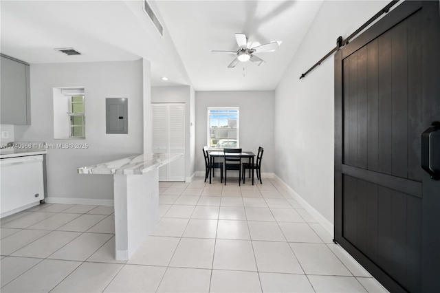 tiled dining room featuring a barn door, electric panel, and ceiling fan