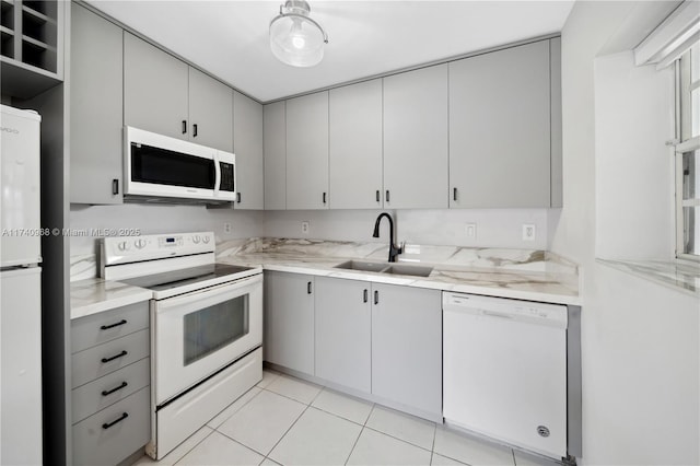 kitchen featuring gray cabinetry, sink, white appliances, and light tile patterned flooring