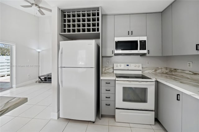 kitchen with light tile patterned flooring, white appliances, gray cabinets, and ceiling fan