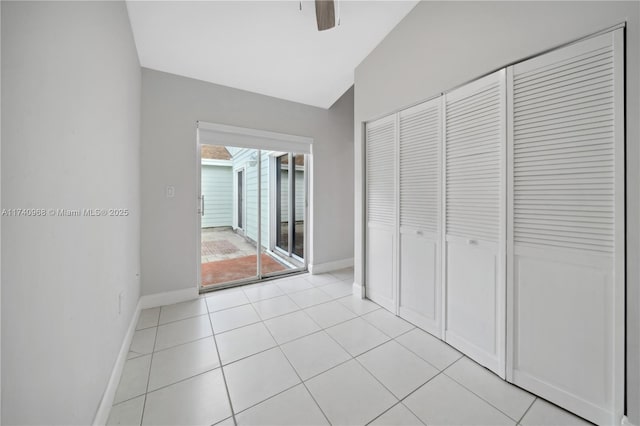 unfurnished bedroom with vaulted ceiling, light tile patterned flooring, ceiling fan, and a closet