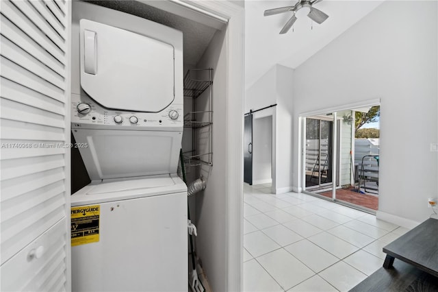 clothes washing area with a barn door, stacked washer and clothes dryer, light tile patterned floors, and ceiling fan