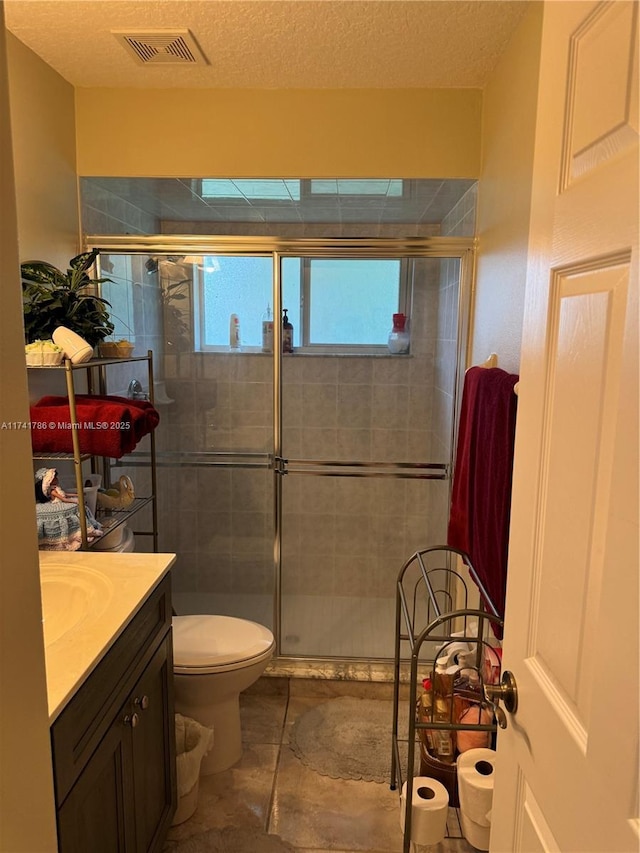 bathroom featuring walk in shower, vanity, toilet, and a textured ceiling