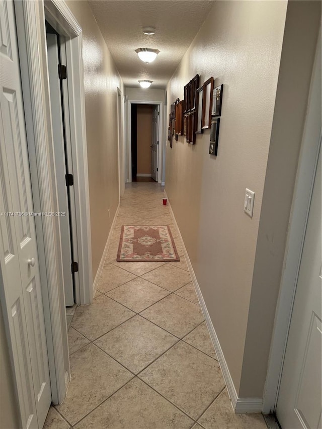 hall with light tile patterned flooring and a textured ceiling