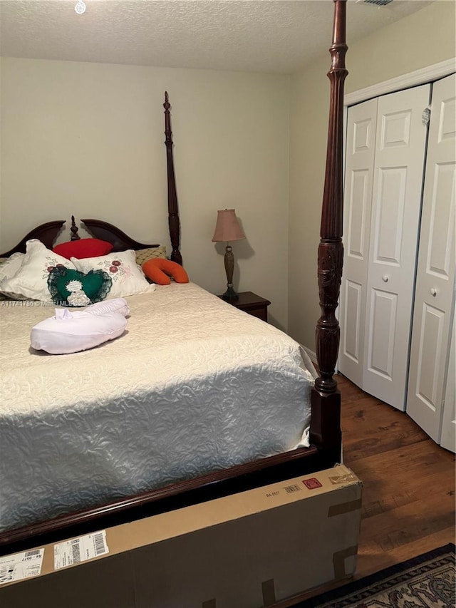 bedroom featuring a closet, dark hardwood / wood-style flooring, and a textured ceiling