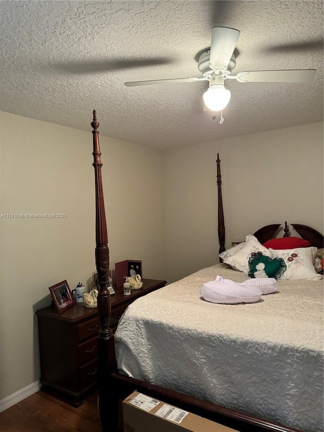 bedroom with ceiling fan, a textured ceiling, and dark hardwood / wood-style flooring