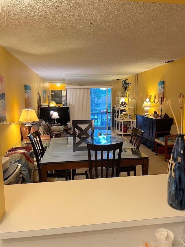 dining space featuring wood-type flooring and a textured ceiling