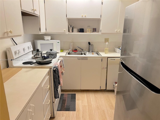 kitchen featuring tasteful backsplash, white cabinetry, sink, light hardwood / wood-style floors, and white appliances