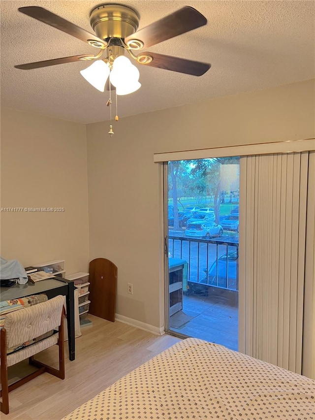 bedroom featuring access to exterior, wood-type flooring, a textured ceiling, and ceiling fan