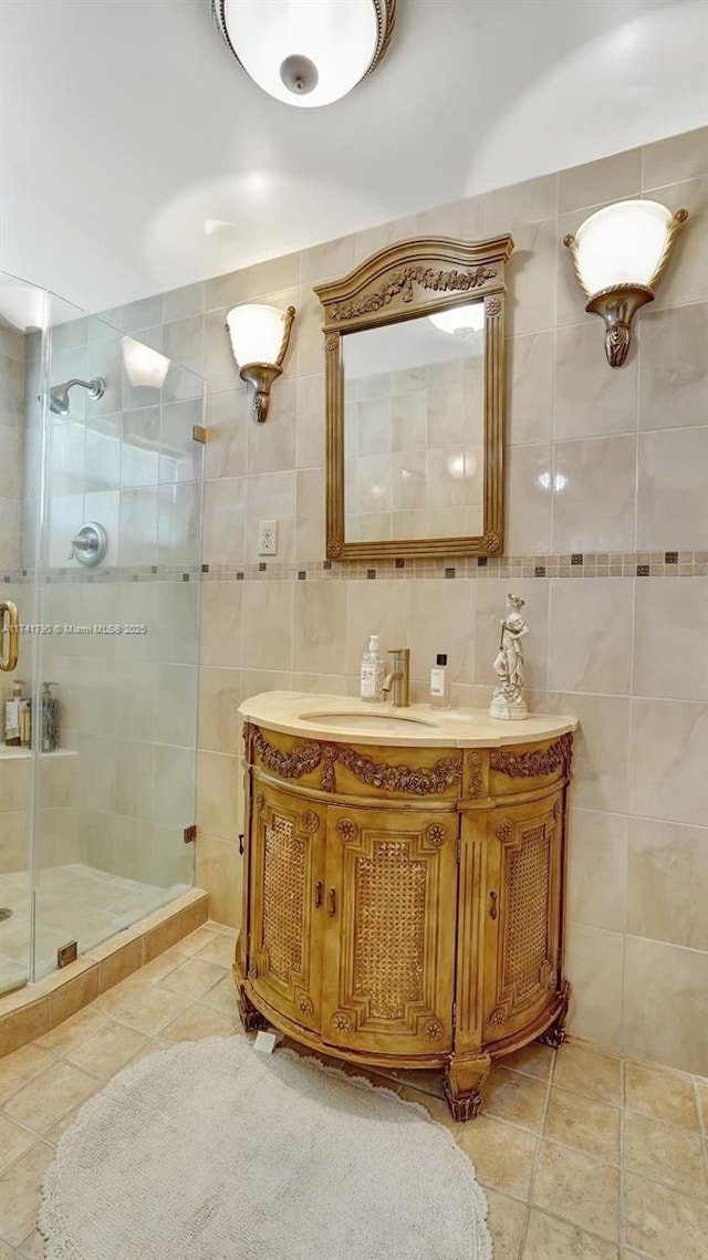 bathroom featuring tile patterned floors, vanity, a shower with shower door, and tile walls