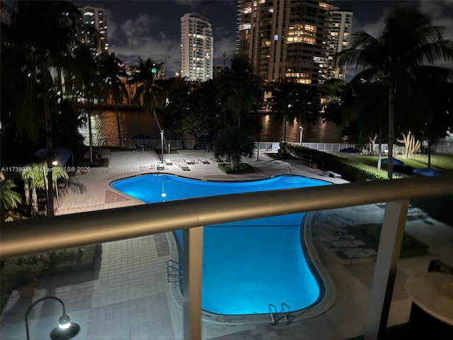 pool at night featuring a patio area