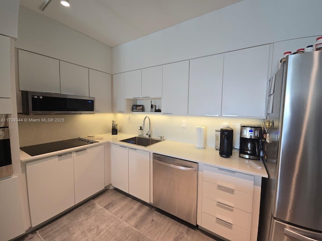 kitchen featuring white cabinetry, sink, light hardwood / wood-style flooring, and appliances with stainless steel finishes