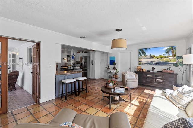 living room with tile patterned flooring, ornamental molding, and a textured ceiling