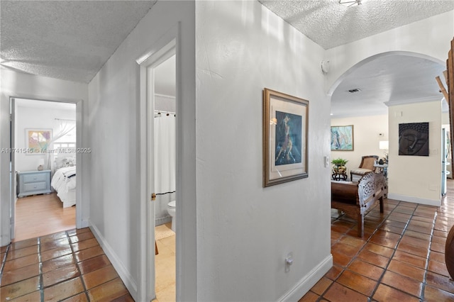 hallway with a textured ceiling and dark tile patterned floors