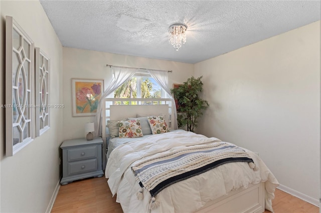 bedroom featuring light hardwood / wood-style floors, a chandelier, and a textured ceiling