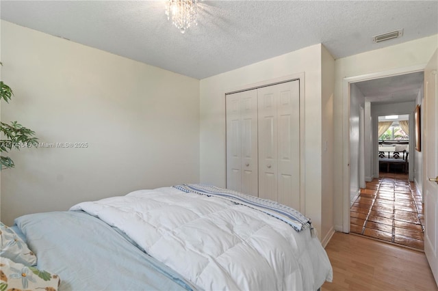 bedroom with a textured ceiling, light wood-type flooring, and a closet