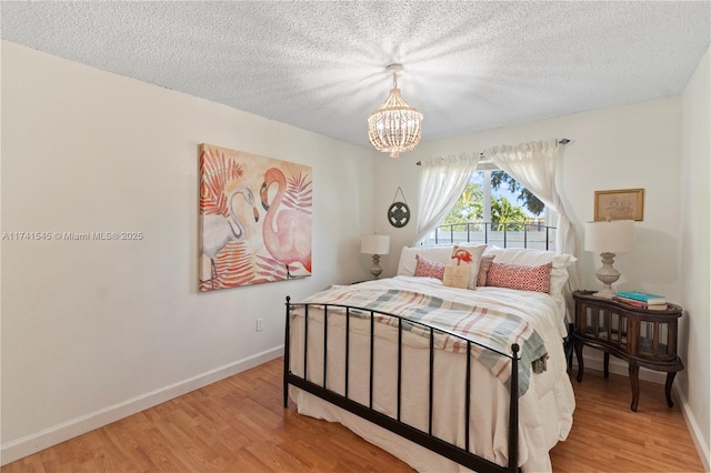 bedroom with a textured ceiling, light hardwood / wood-style floors, and a chandelier