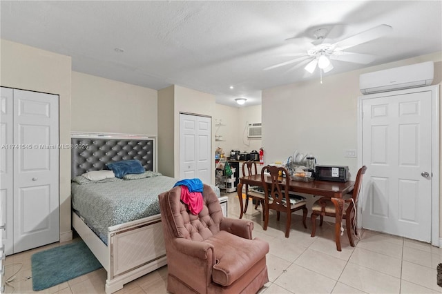 tiled bedroom with ceiling fan, two closets, and a wall unit AC