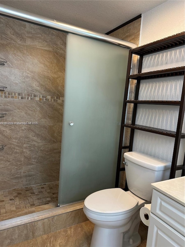 bathroom featuring vanity, an enclosed shower, a textured ceiling, and toilet