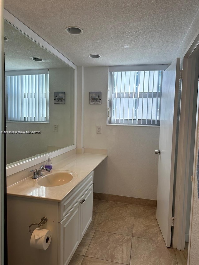 bathroom featuring vanity, a healthy amount of sunlight, tile patterned floors, and a textured ceiling