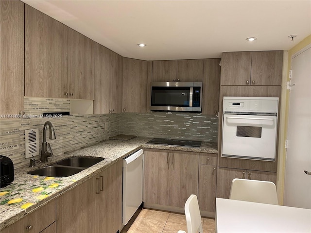 kitchen featuring sink, light stone counters, and white appliances