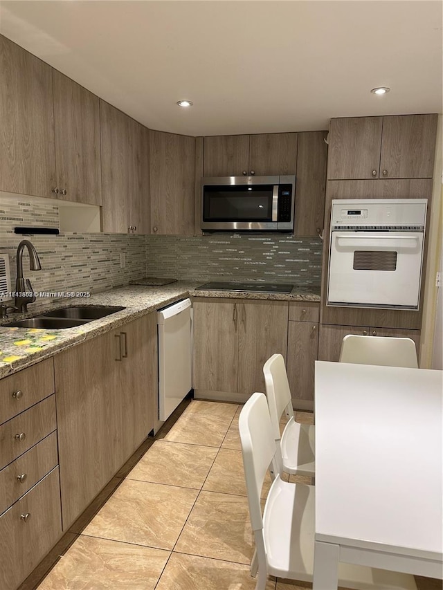 kitchen with sink, light stone counters, tasteful backsplash, light tile patterned floors, and white appliances