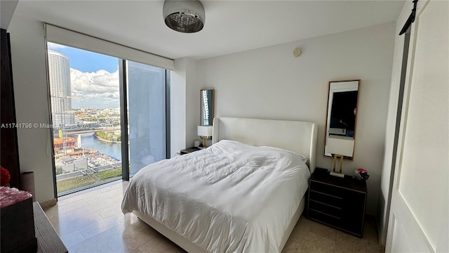 bedroom featuring a water view, expansive windows, and access to outside