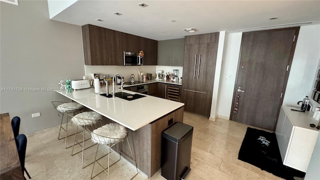 kitchen with sink, beverage cooler, a kitchen bar, and kitchen peninsula