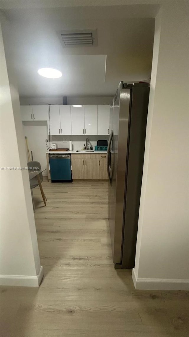 kitchen featuring sink, white cabinetry, light hardwood / wood-style flooring, stainless steel refrigerator, and dishwasher