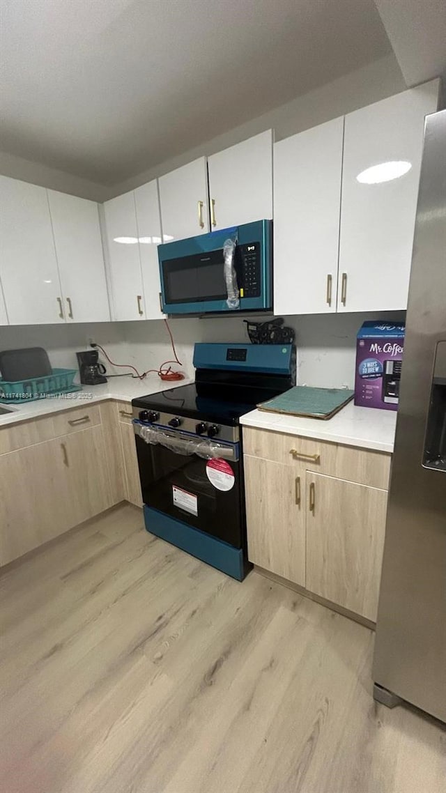 kitchen with appliances with stainless steel finishes, light brown cabinetry, light hardwood / wood-style floors, and white cabinets