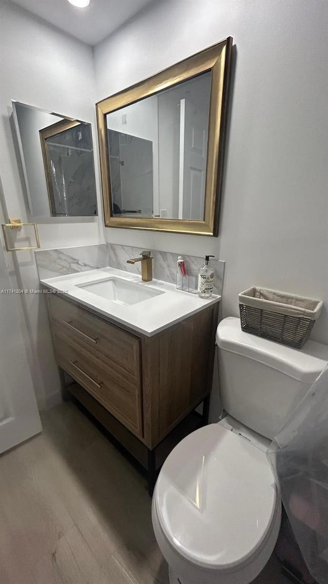 bathroom with vanity, hardwood / wood-style flooring, decorative backsplash, and toilet