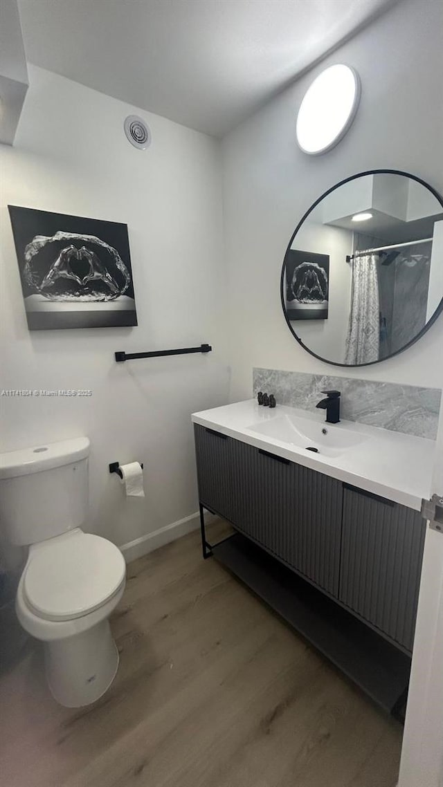 bathroom featuring vanity, wood-type flooring, toilet, and a shower with shower curtain