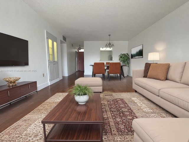 living area featuring wood finished floors, visible vents, baseboards, an inviting chandelier, and a textured ceiling