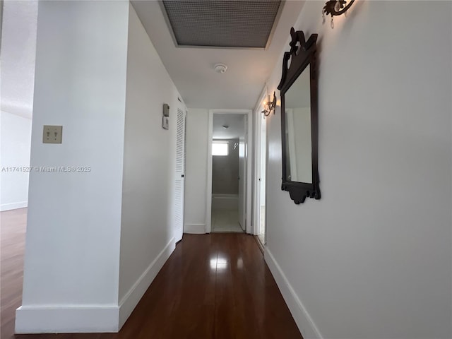 hall with visible vents, wood finished floors, and baseboards