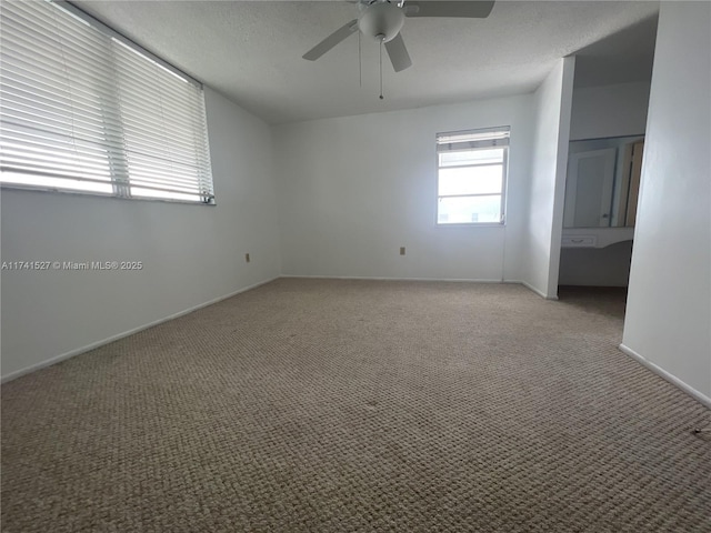 spare room featuring light carpet, ceiling fan, a textured ceiling, and baseboards