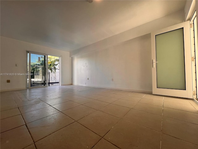 empty room with light tile patterned floors and baseboards