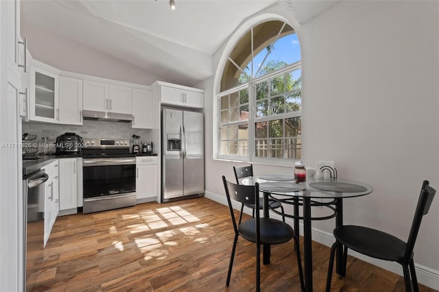 kitchen with lofted ceiling, appliances with stainless steel finishes, white cabinetry, tasteful backsplash, and light wood-type flooring