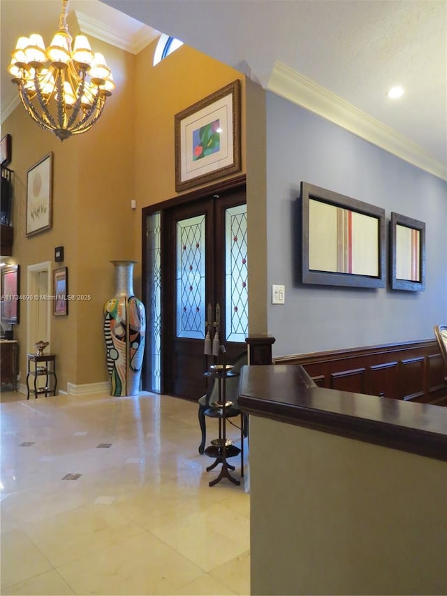 entryway featuring crown molding, a towering ceiling, french doors, and a notable chandelier