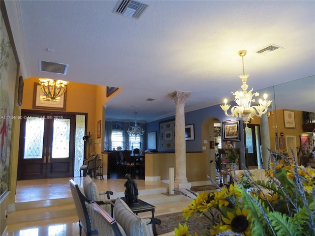 interior space featuring ornate columns, ornamental molding, a notable chandelier, and french doors