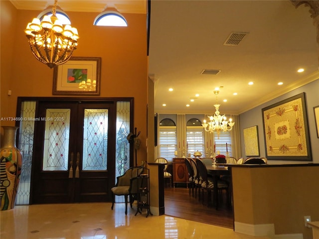 foyer entrance with an inviting chandelier, tile patterned floors, crown molding, and french doors