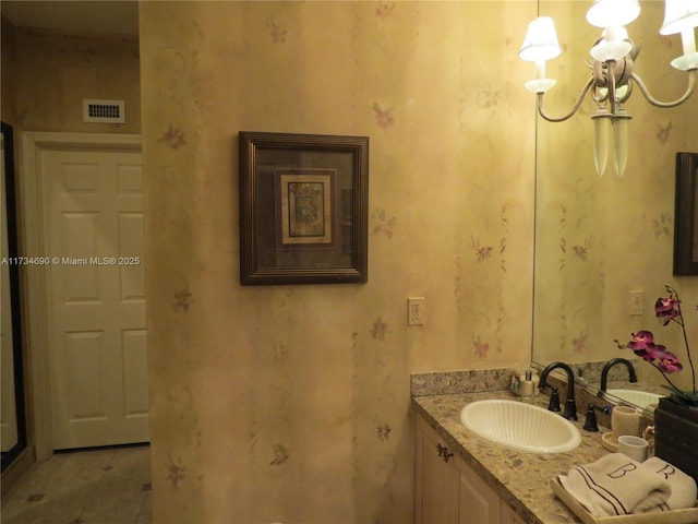 bathroom with an inviting chandelier, vanity, and tile patterned flooring