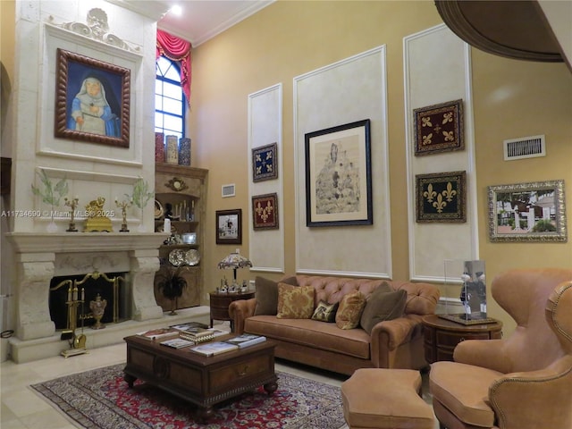 living room featuring a towering ceiling, ornamental molding, and a premium fireplace