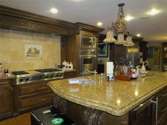 kitchen featuring crown molding, a spacious island, built in appliances, light stone counters, and wine cooler