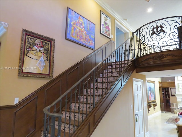 staircase with ornamental molding and a towering ceiling