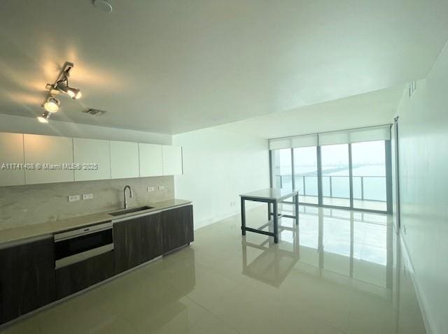 kitchen featuring white cabinetry, dishwasher, sink, and backsplash