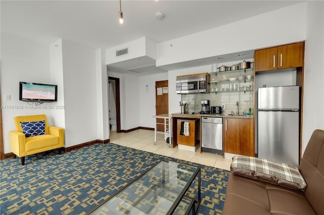 kitchen featuring stainless steel appliances, sink, light tile patterned floors, and decorative backsplash