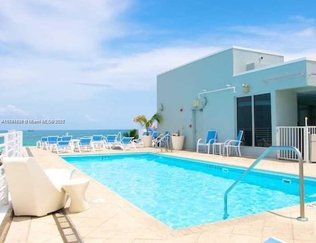 view of pool featuring a water view and a patio area