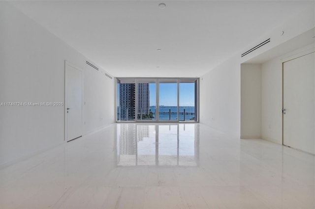 unfurnished room with expansive windows and a water view