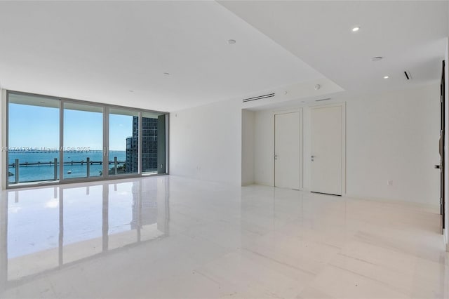 unfurnished room featuring a water view and expansive windows