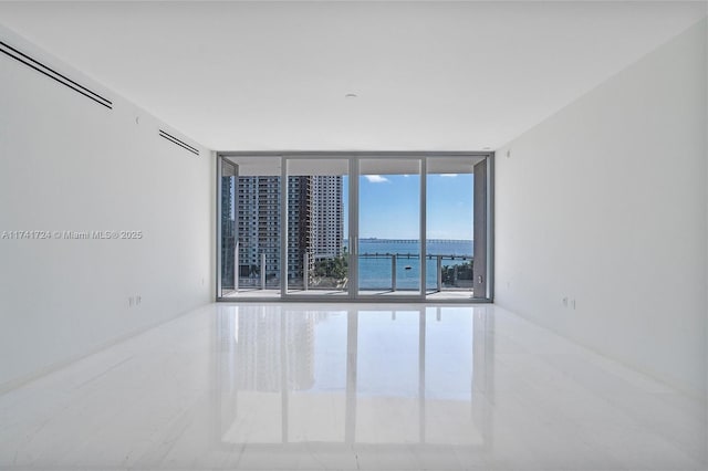 spare room with a water view and floor to ceiling windows